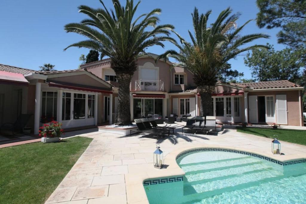 une maison avec une piscine et des palmiers dans l'établissement Villa privée indépendante et Luxueuse au calme, à Narbonne