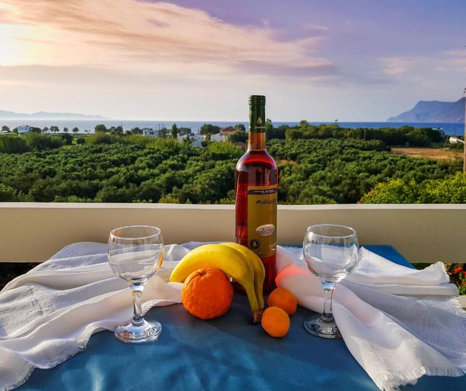 Una botella de vino y dos copas en una mesa. en Marianos Apartments en Kíssamos