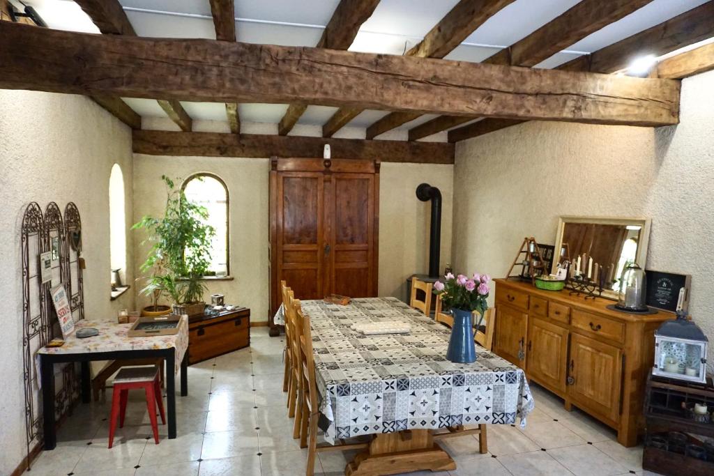 a dining room with a table and chairs and a room with wooden ceilings at La Bergerie De Valerie in Arthès