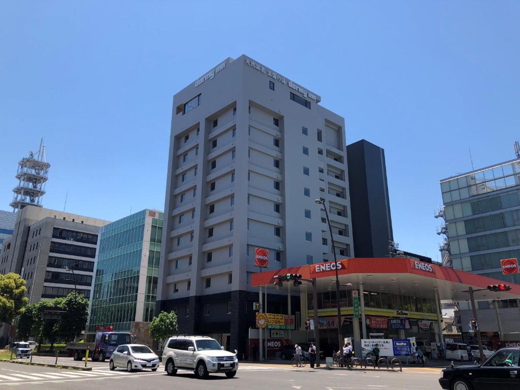高松多美迎高松中央公园前酒店的一座高大的白色建筑,汽车停在城市里