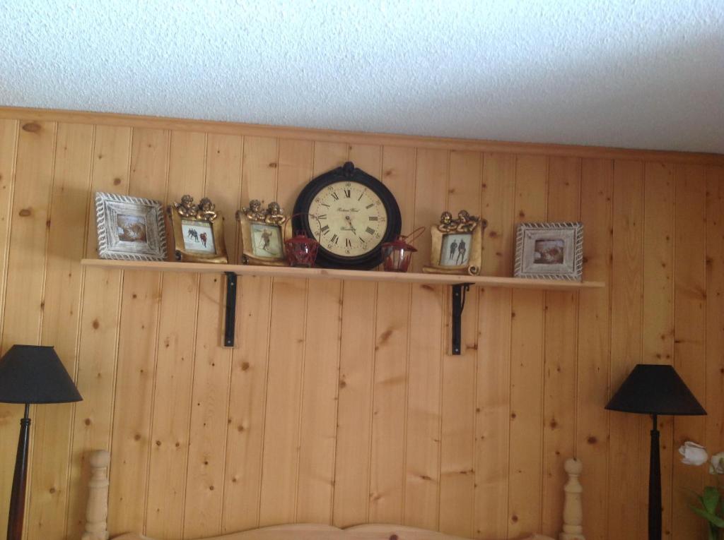 a clock on a wooden wall with framed pictures at Petit Ours in Villars-sur-Ollon