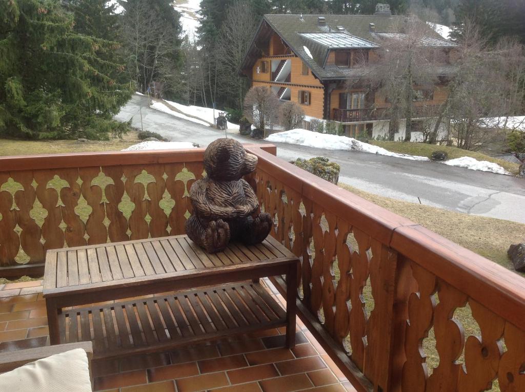 a statue sitting on a bench on a balcony at Petit Ours in Villars-sur-Ollon