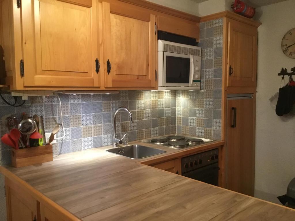 a kitchen with wooden cabinets and a sink and a microwave at Petit Ours in Villars-sur-Ollon