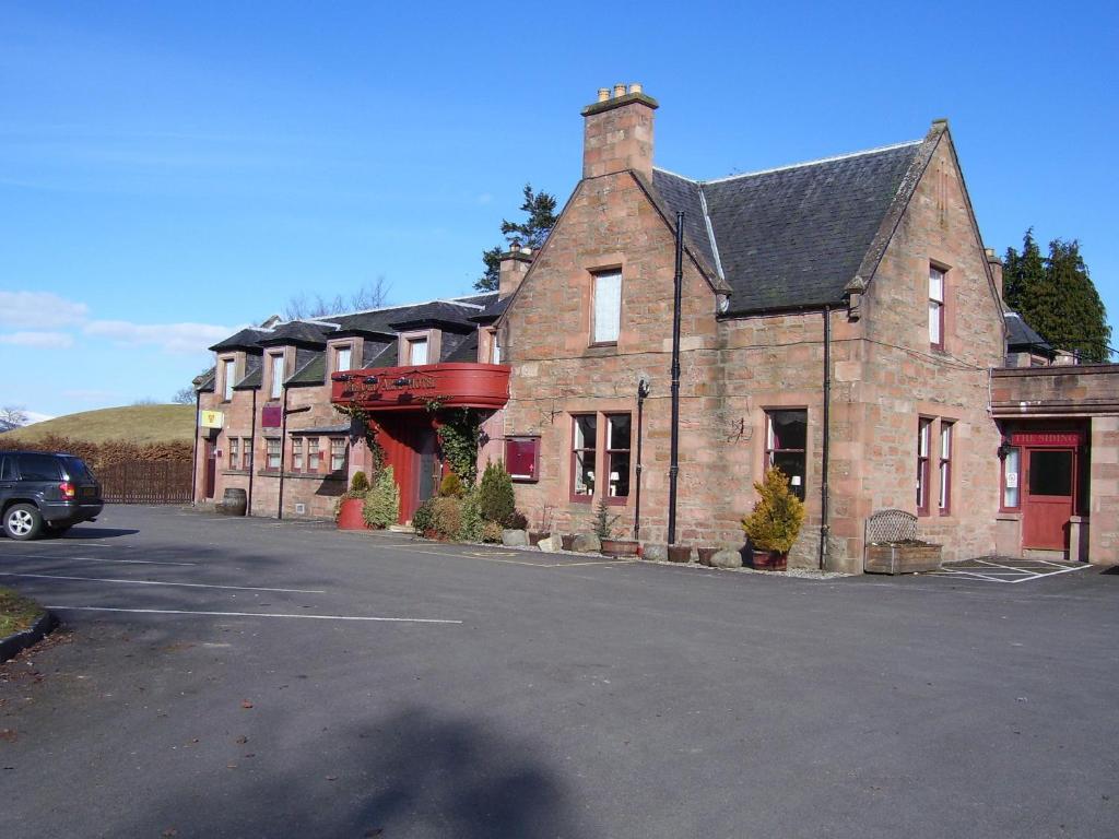 an old brick building with a parking lot in front of it at Ord Arms Hotel in Muir of Ord