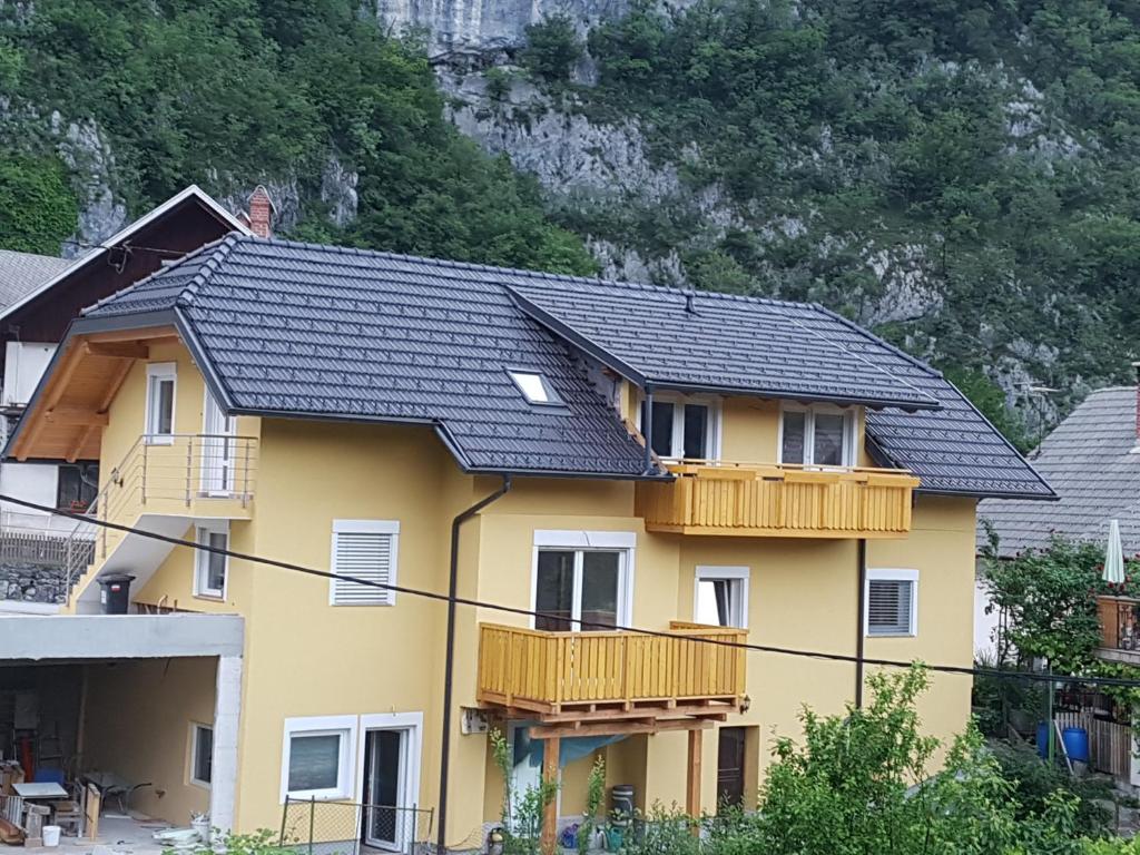 ein gelbes Haus mit schwarzem Dach in der Unterkunft Apartmaji Zupan in Bohinjska Bela