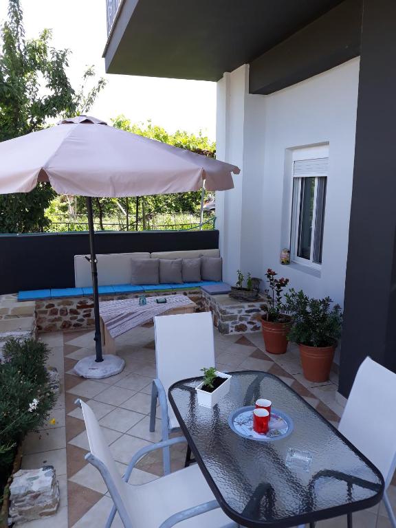 a patio with a table and chairs and an umbrella at Filoxenia Apartments in Skala Sotiros