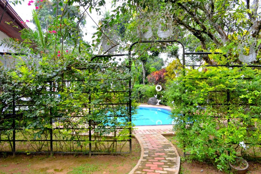 a pool in a garden with a gate and plants at Sama Uyana Holiday Bungalow in Gampola