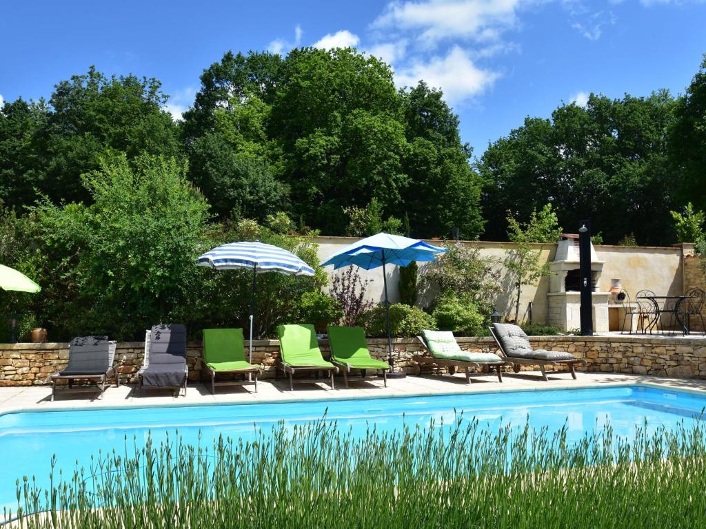 a pool with chairs and umbrellas next to at Superb Holiday Home in Busse with Swimming Pool in Villefranche-du-Périgord