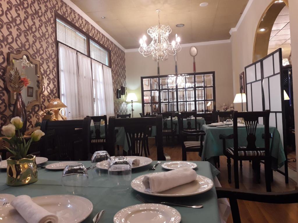 comedor con mesa, sillas y lámpara de araña en Hostal Hispalis, en Gandul