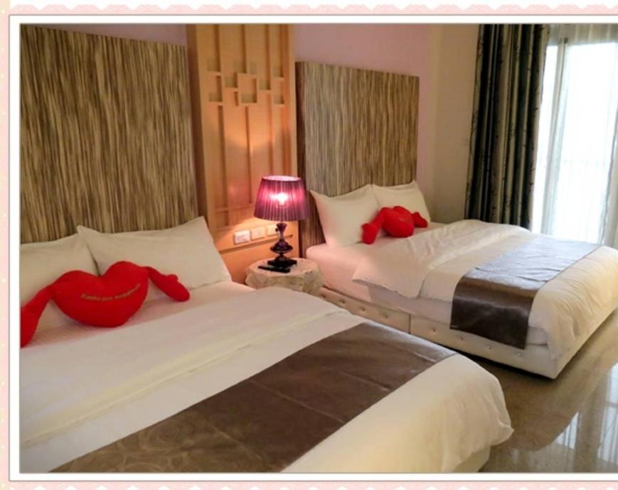 台東市的住宿－小菲民宿 ，两张位于酒店客房的床铺,配有红色枕头