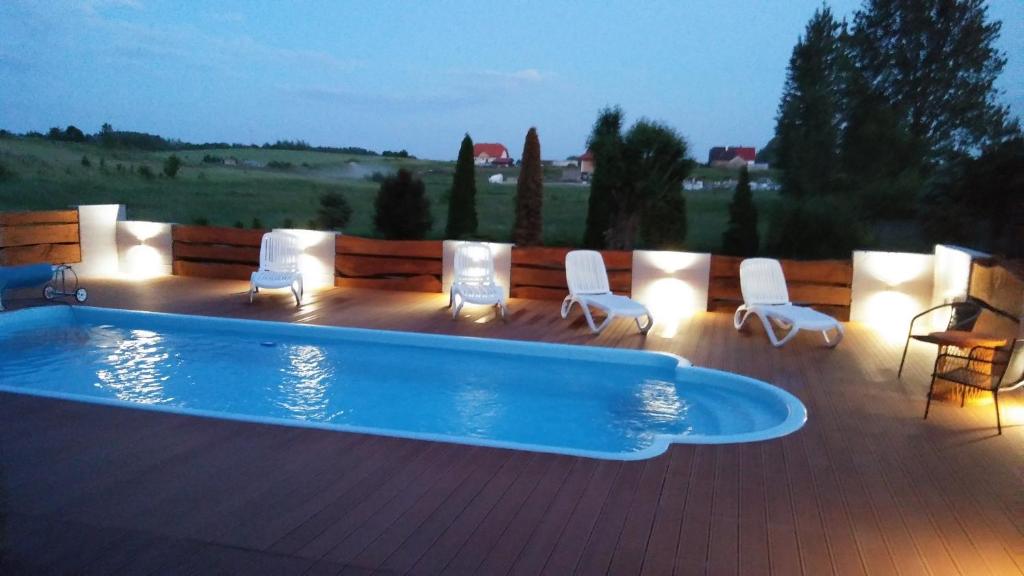 una piscina en una terraza con sillas y luces en Pensjonat pod Kasztanem, en Ełk