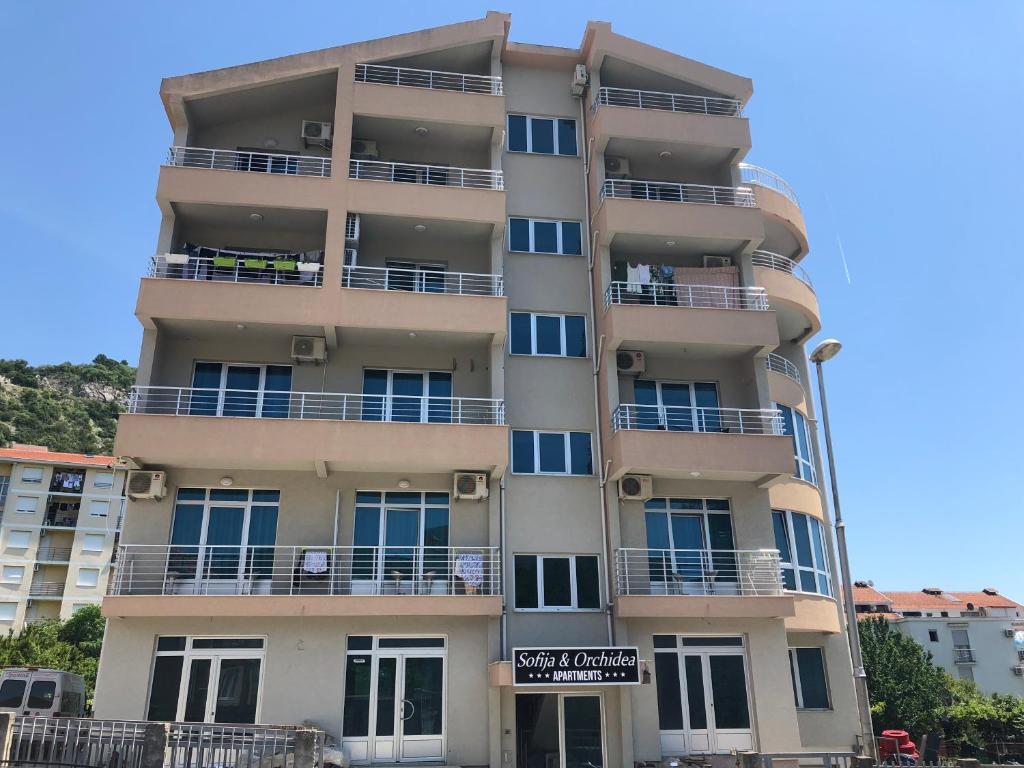 un edificio de apartamentos alto con un cartel delante en Apartment Sofija, en Budva