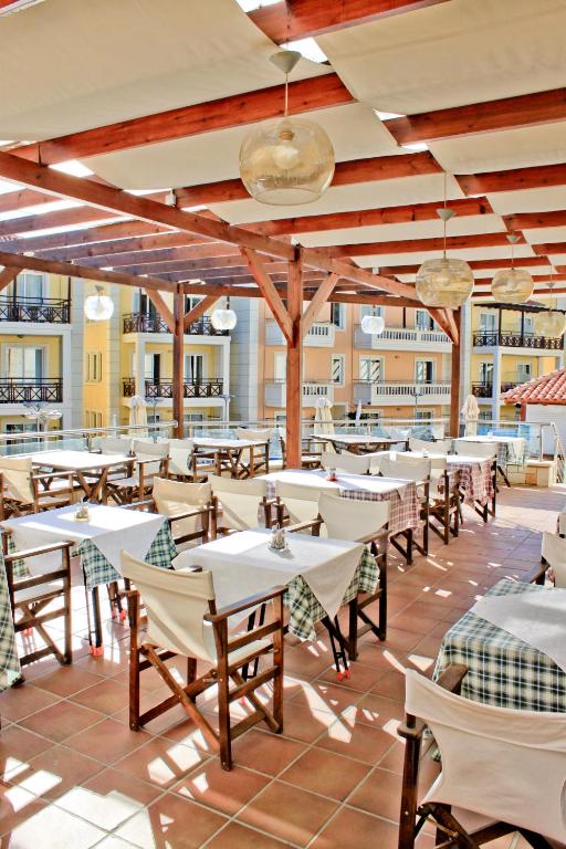 restauracja ze stołami i krzesłami na patio w obiekcie Porto Kalamaki Hotel w mieście Kalamaki