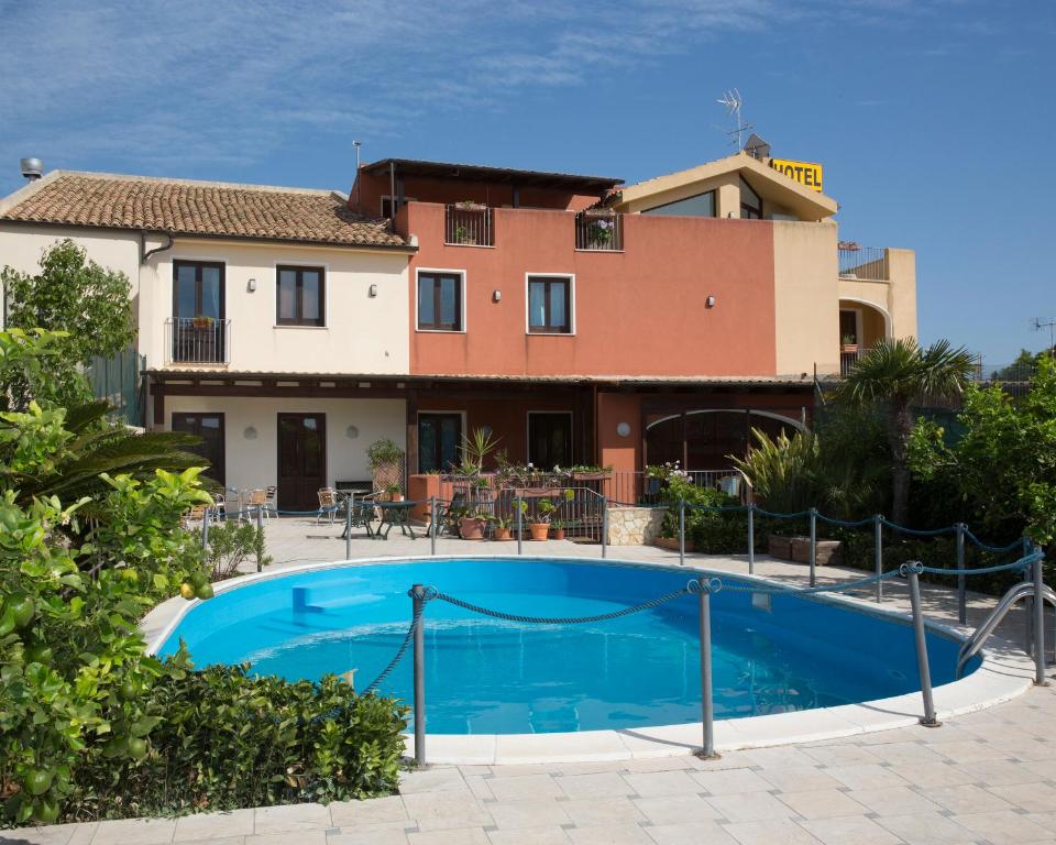 a villa with a swimming pool in front of a house at Hotel Isola Di Mozia in Marsala