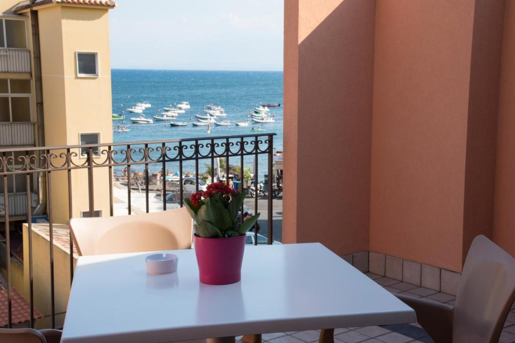 a table with a plant on a balcony with a view of the ocean at Acitrezza B&B in Acitrezza
