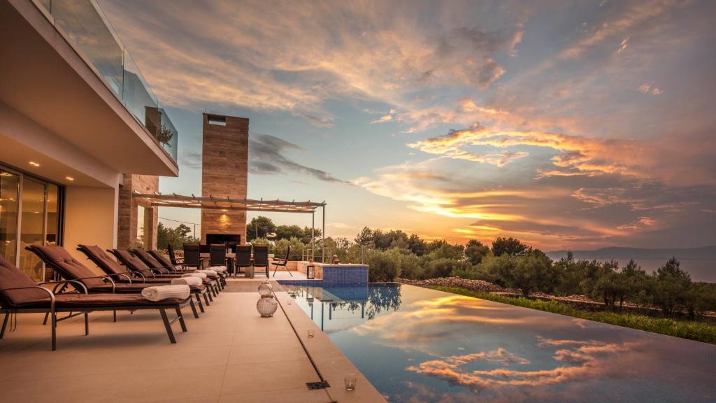 a house with a swimming pool with a sunset at Villa Ana in Splitska