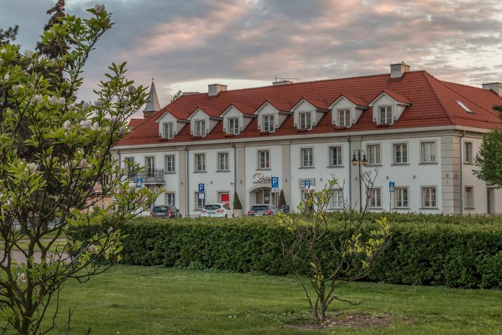 un grand bâtiment blanc avec un toit rouge dans l'établissement Hotel Rozbicki, à Włocławek