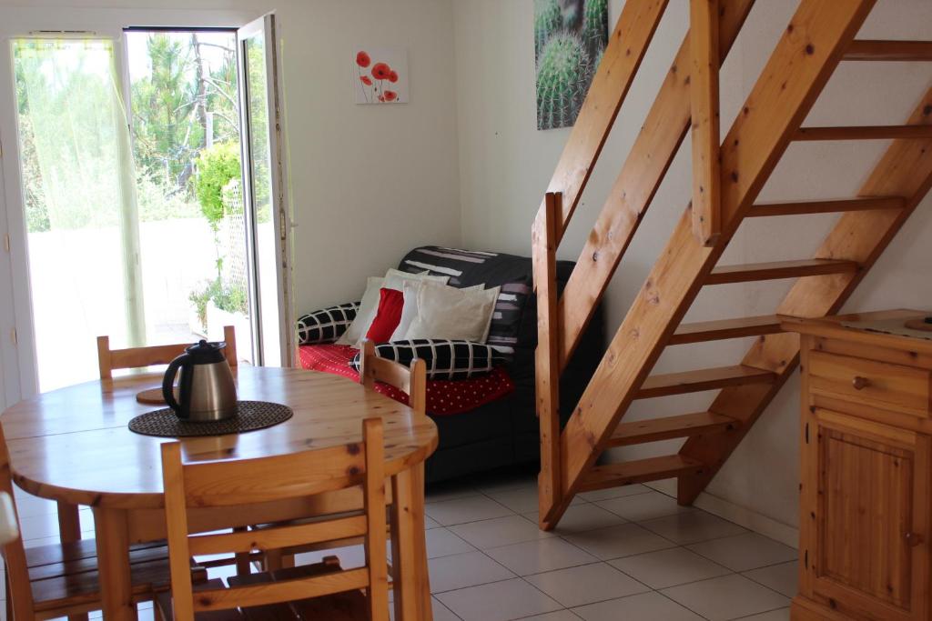 ein Esszimmer mit einem Tisch und einer Treppe in der Unterkunft Maison Saint Hilaire de Riez, 300m de la plage in Saint-Hilaire-de-Riez