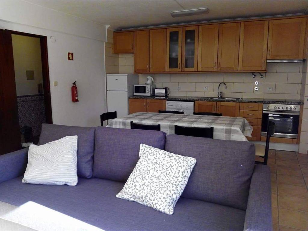 ein Wohnzimmer mit einem lila Sofa vor einer Küche in der Unterkunft Casinhas da Praia in São Martinho do Porto