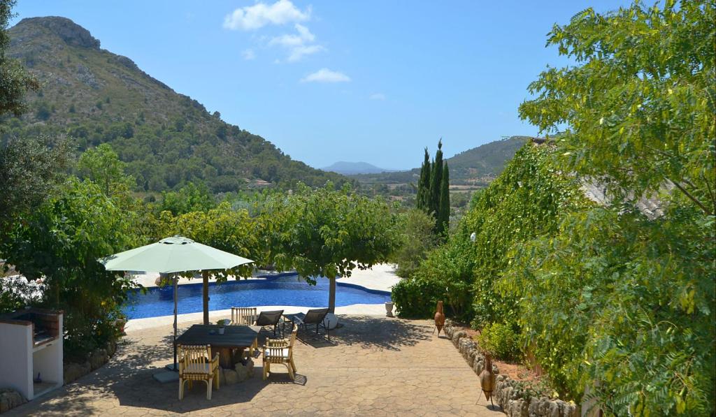 un patio con mesa y sombrilla junto a la piscina en Cantó, en Alcudia