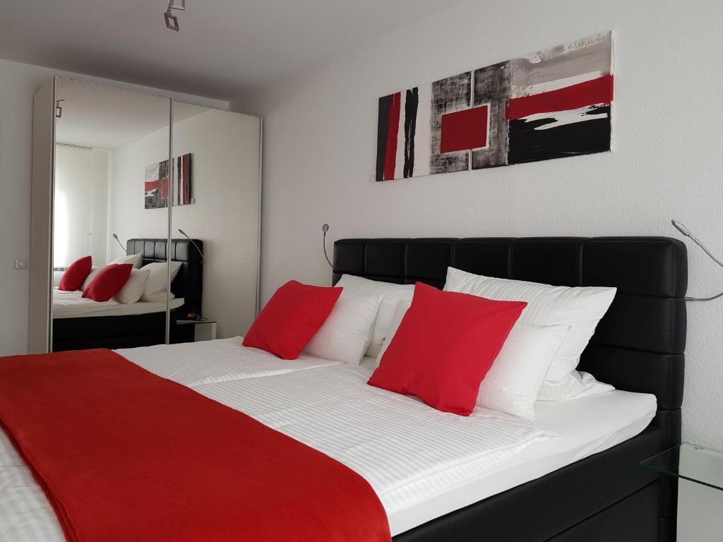 een slaapkamer met een groot bed met rode en witte kussens bij Innovative 2-Zimmer-Ferienwohnung am Kurpark in Bad Kreuznach