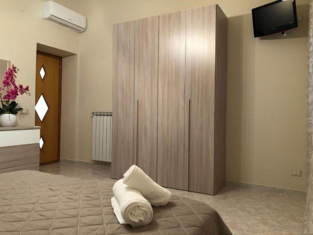 a bedroom with a large wooden cabinet with towels on a bed at Tortora House in Scafati