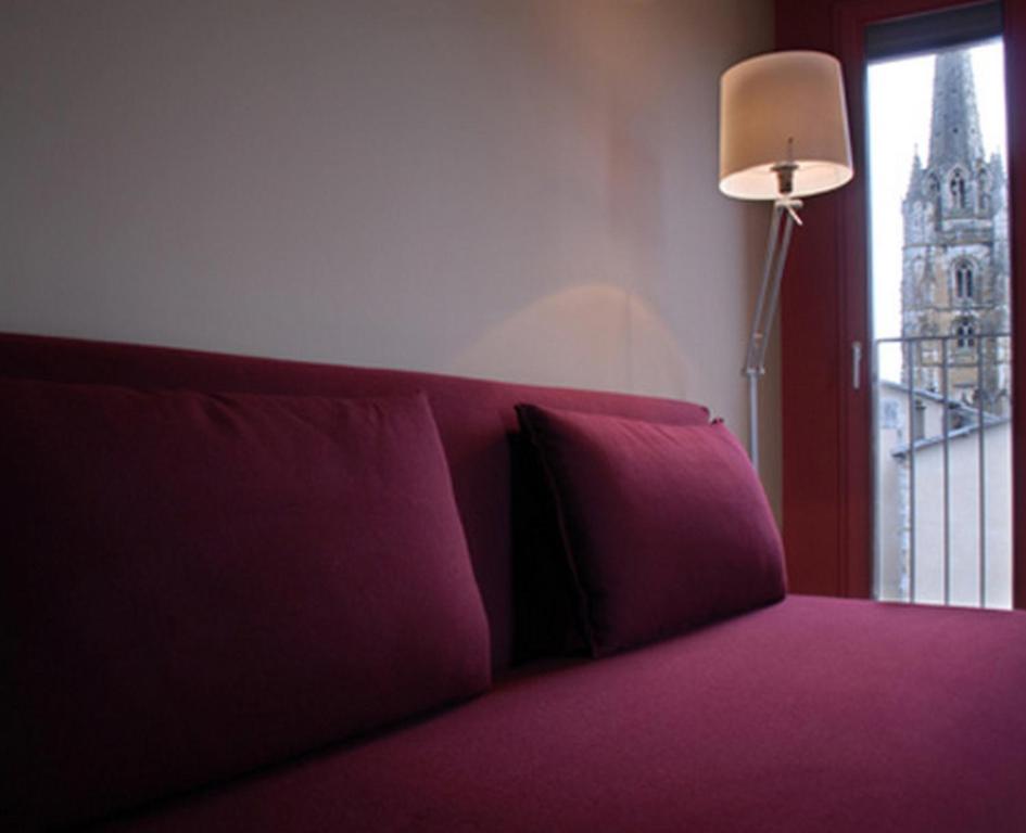a purple couch with a lamp and a window at Temporesidence Cathedrale in Bayonne