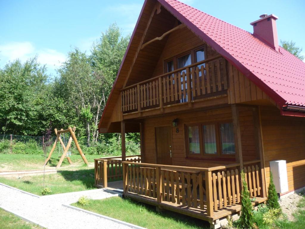 a large wooden house with a playground in the background at Domki Nad Krystaliczną Zatoką in Polańczyk