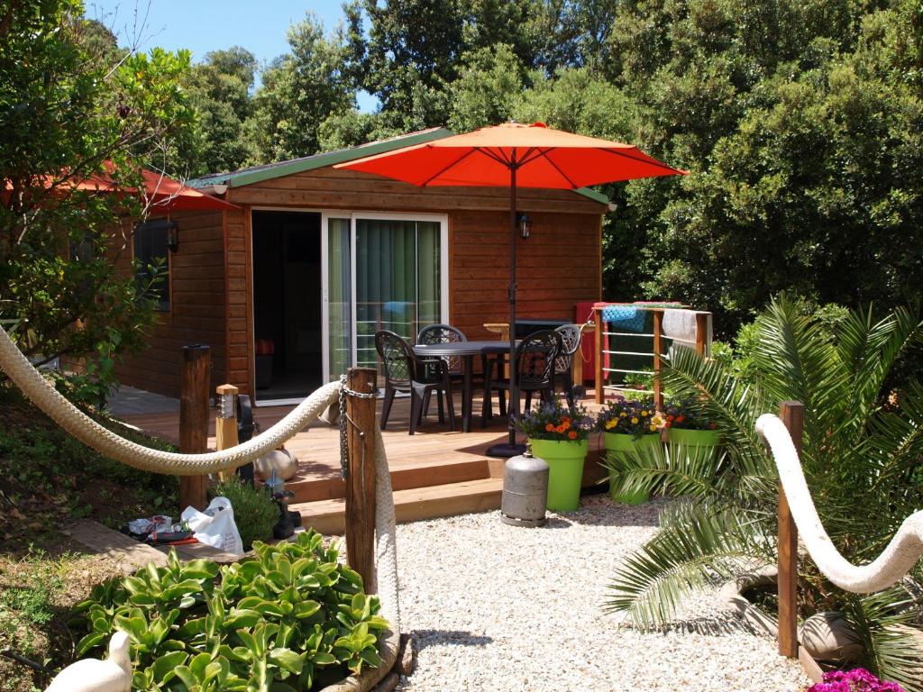 a small house with a patio with an umbrella at Le petit chalet in Porticcio