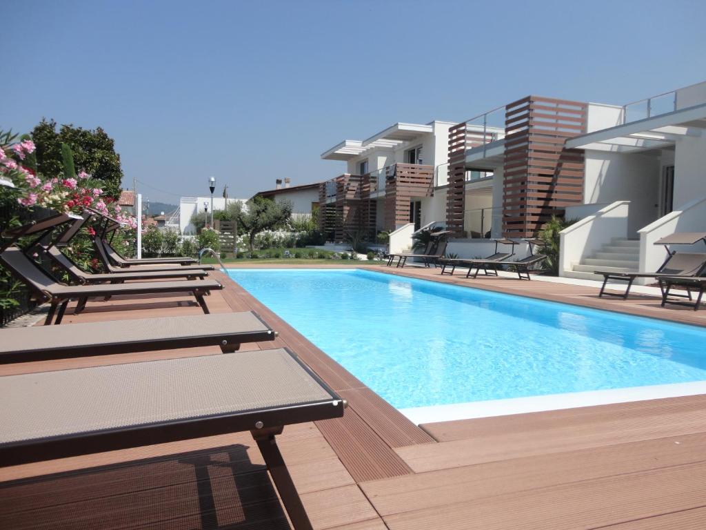 a swimming pool with chaise lounges next to a building at Bio Suites PACINOTTI in Bardolino