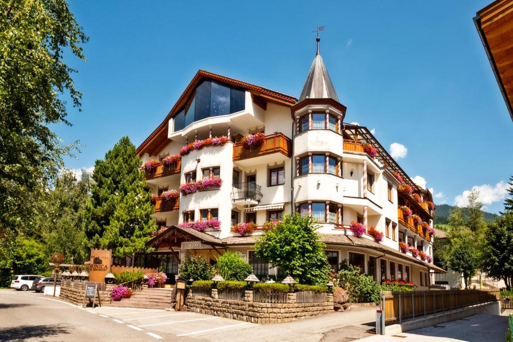 - un grand bâtiment blanc avec des fleurs dans l'établissement Hotel Villa Monica, à Dobbiaco