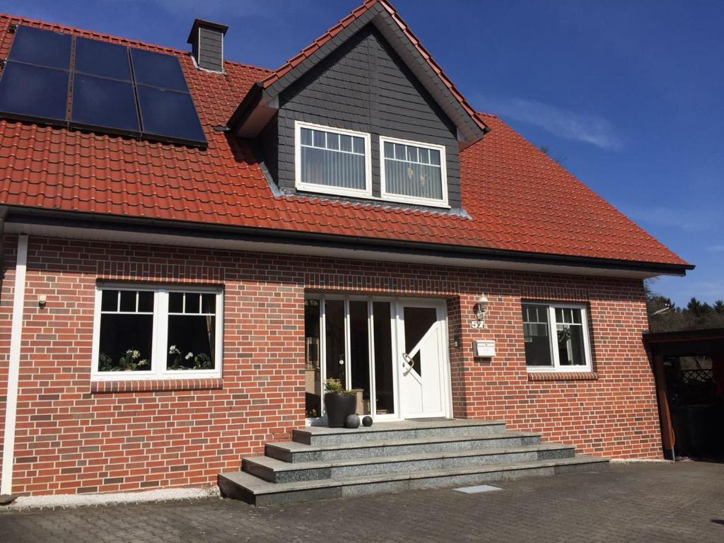 een rood bakstenen huis met een witte deur en een trap bij Ferienwohnung am Dörenberg in Georgsmarienhütte