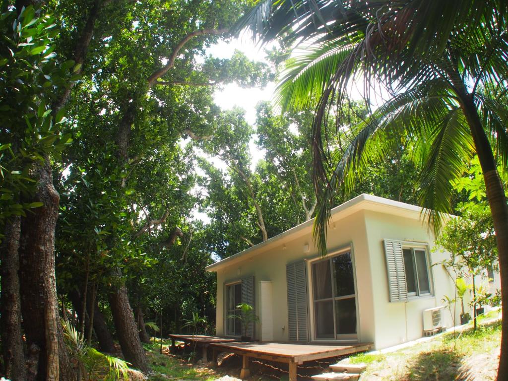 a small white house in the middle of trees at Kuganipi Beachside Inn Iriomote in Iriomote