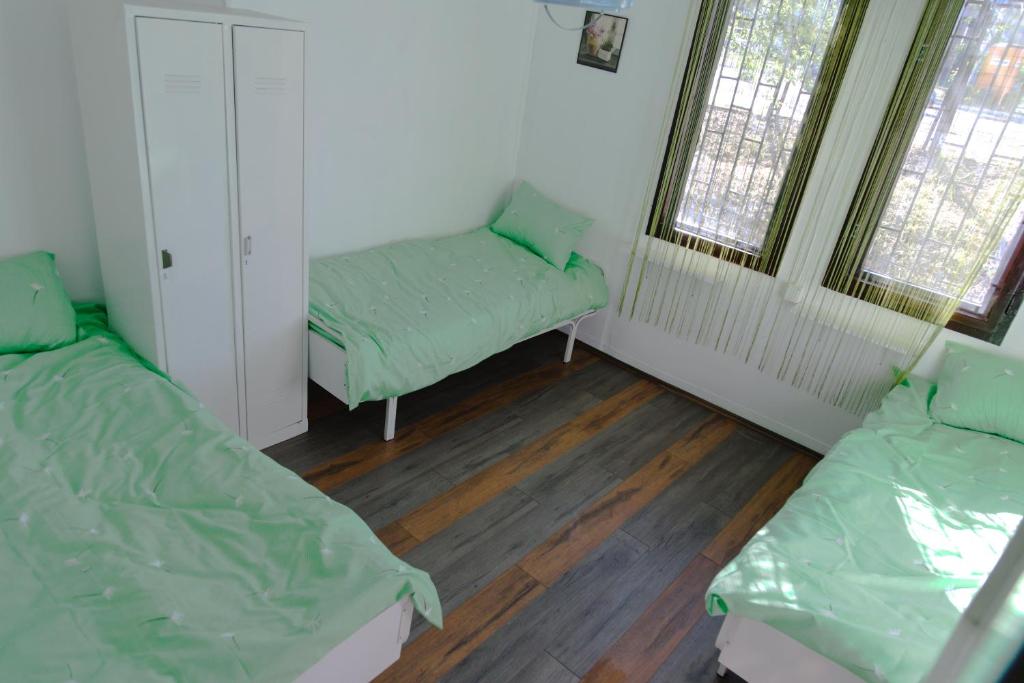 a room with two beds and a bench and two windows at Hostel Belgrade Shungit Dragana Jeftića br 10 in Belgrade