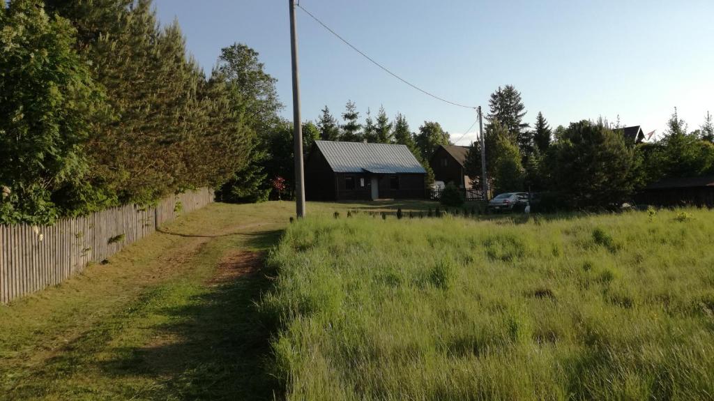 a field of grass with a house and a fence at Domek letniskowy w Rygoli in Rygol