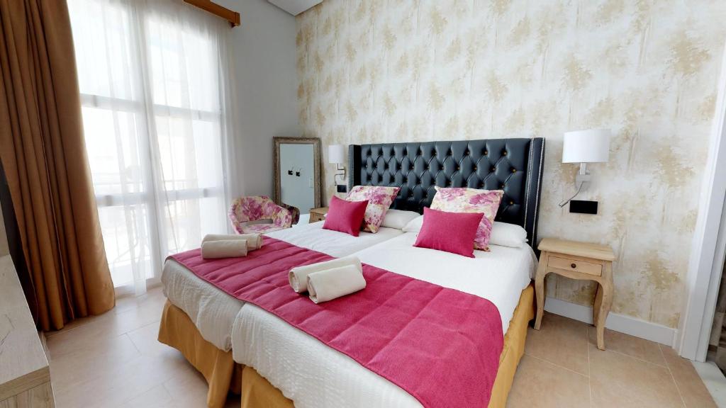 a large bedroom with a large bed with pink pillows at Hostal Boutique La Española by Bossh Hotels in Rota