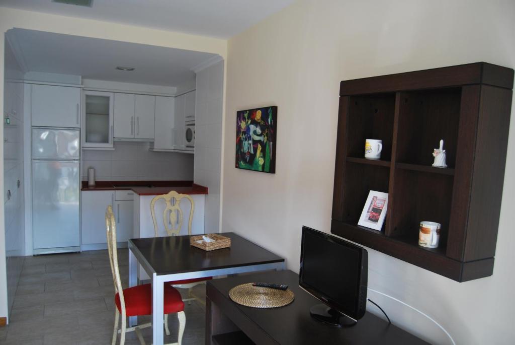 a living room with a desk with a computer and a kitchen at Playa Colina in Argoños