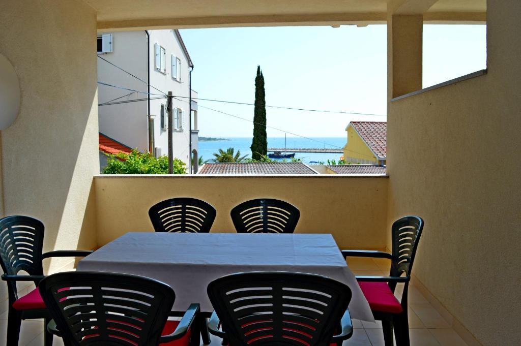 een tafel en stoelen op een balkon met uitzicht op de oceaan bij Apartments Mačak in Novalja