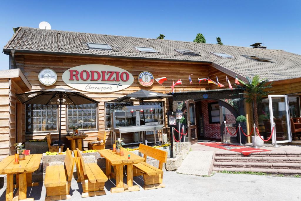 a restaurant with wooden tables in front of a building at Hotel Restaurant Rodizio Paderborn in Altenbeken