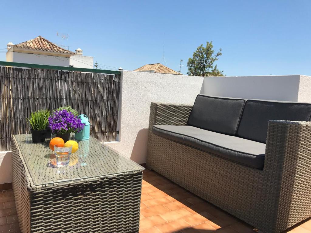 een patio met een rieten stoel en een tafel met fruit bij Tavira near the center - two bedroom with balcony in Tavira