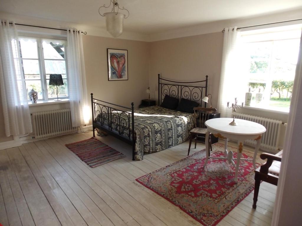 a bedroom with a bed and a table and two windows at The Garden Hill Hotel in Vallåkra