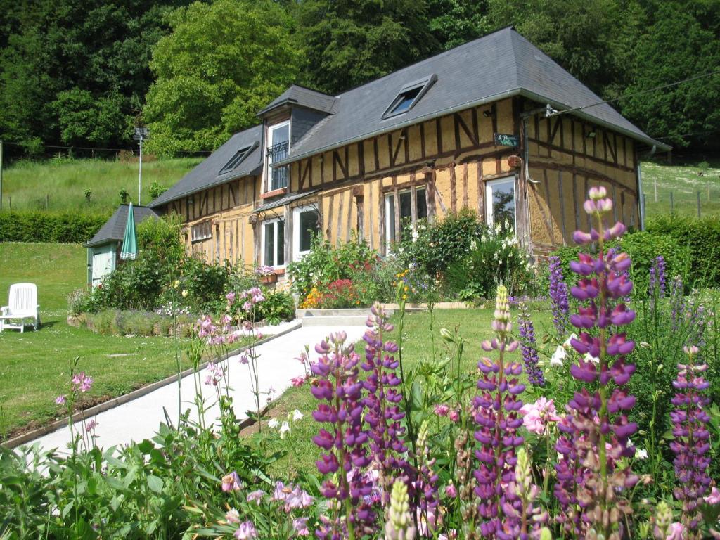 uma casa de madeira com flores em frente em La Pomme Verte em Authou