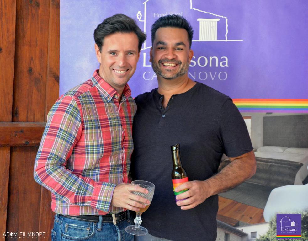 two men standing next to each other holding a bottle of wine at La Casona de Castilnovo - Gay Men Only in Valdesaz