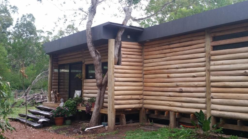 eine Holzhütte mit einem Baum in der Unterkunft Chalet Los Troncos in Sauce de Portezuelo