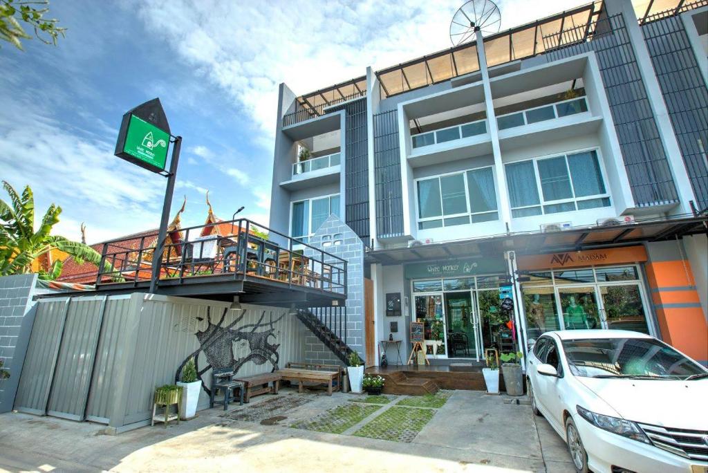 une voiture blanche garée devant un bâtiment dans l'établissement White Monkey Guesthouse, à Phetchaburi