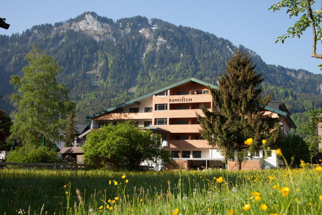 a hotel in the mountains with a field of flowers at Hotel Kanisfluh in Mellau