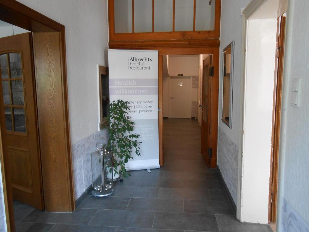 a hallway with a sign on the wall and a plant at Albrecht's Hotel & Restaurant GmbH in Wiedensahl