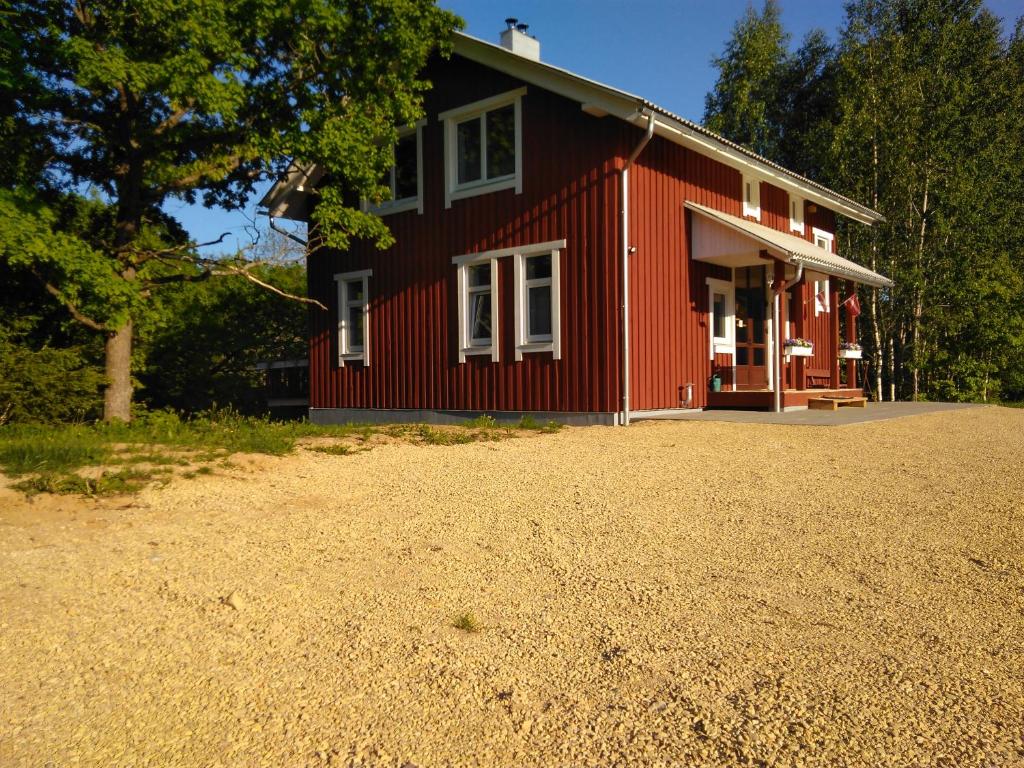 a red house with a gravel driveway in front of it at Toma pirts LIELĀ in Ikšķile