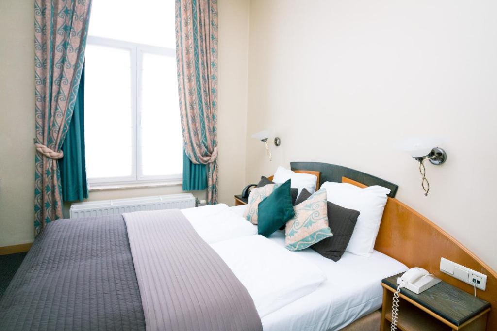 a bedroom with a white bed with pillows and a window at Hotel Moby Dick by WP hotels in Blankenberge