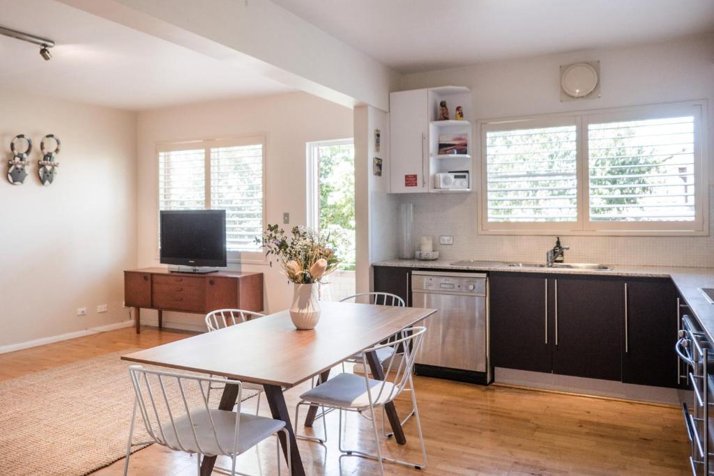 cocina y comedor con mesa y sillas en Stylish and Spacious Beach Apartment en Sídney